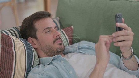 Téléchargez les photos : Casual Man using Smartphone while Sleeping in Bed - en image libre de droit