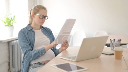 Foto de Mujer hermosa embarazada leyendo documentos en el trabajo - Imagen libre de derechos