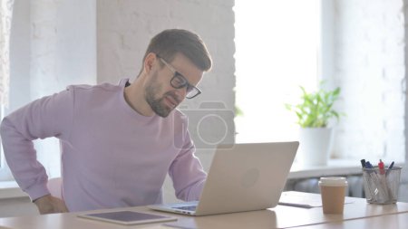Photo for Young Adult Man with Back Pain at Work - Royalty Free Image