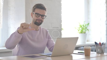 Photo for Young Adult Man Showing Thumbs Down While using Laptop - Royalty Free Image