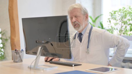 Foto de The Old Doctor having Back Pain while Working on Computer - Imagen libre de derechos