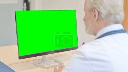 Téléchargez les photos : The Old Doctor Working on Desktop with Chroma Key Screen - en image libre de droit