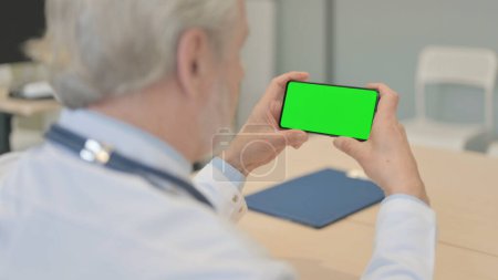 Foto de The Close Up of Old Doctor Watching Smartphone with Green Screen - Imagen libre de derechos