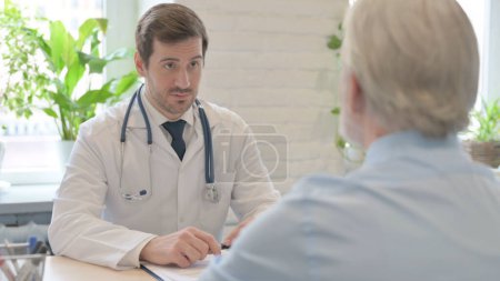 Téléchargez les photos : The Young Doctor Talking with Old Patient in Clinic - en image libre de droit