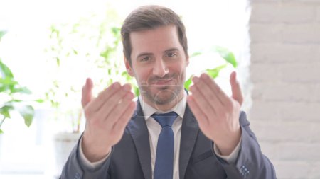 Photo for The Young Adult Businessman Pointing at the Camera and Inviting in Office - Royalty Free Image