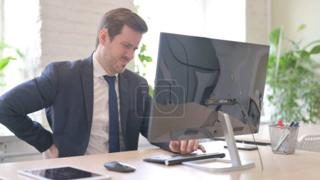 Photo for The Young Adult Businessman having Back Pain while Working on Computer - Royalty Free Image