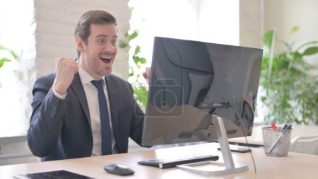 Photo for The Young Adult Businessman Celebrating Success while Working on Computer - Royalty Free Image