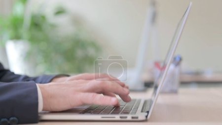 Foto de The Side View of Young Businessman Typing on Laptop - Imagen libre de derechos