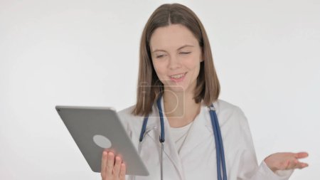 Téléchargez les photos : Appel vidéo sur tablette par jeune médecin sur fond blanc - en image libre de droit