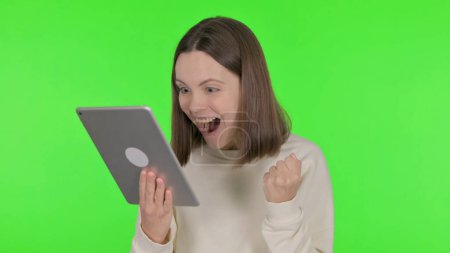 Téléchargez les photos : Casual Woman Célébration du succès sur tablette sur fond vert - en image libre de droit