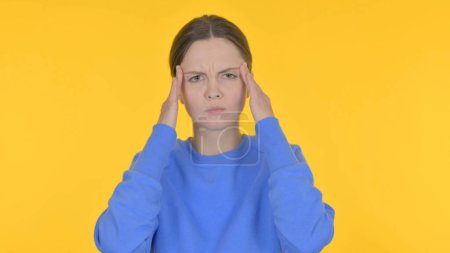 Téléchargez les photos : Femme occasionnelle tendue avec maux de tête sur fond jaune - en image libre de droit