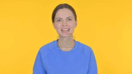 Téléchargez les photos : Femme occasionnelle parlant sur appel vidéo en ligne sur fond jaune - en image libre de droit