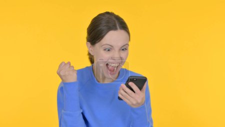 Foto de Mujer casual celebrando en Smartphone sobre fondo amarillo - Imagen libre de derechos