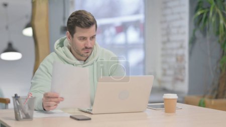 Photo for Young Adult Man Working on Laptop and Documents - Royalty Free Image