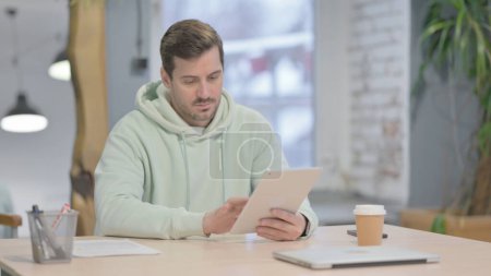 Téléchargez les photos : Young Adult Man using Digital Tablet, Browsing Internet - en image libre de droit