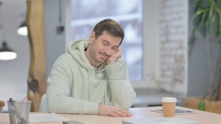 Photo for Young Adult Man Sleeping while Sitting at Work - Royalty Free Image