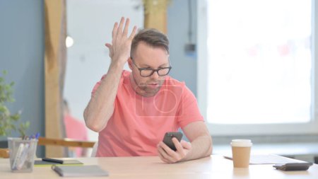 Foto de Upset Young Adult Man Reacting to Loss on Smartphone - Imagen libre de derechos