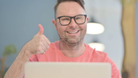 Photo for Close Up of Thumbs Up by Young Adult Man Working on Laptop - Royalty Free Image