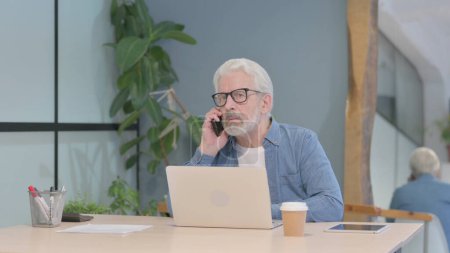 Téléchargez les photos : Angry Senior Old Man Talking on Phone at Work - en image libre de droit