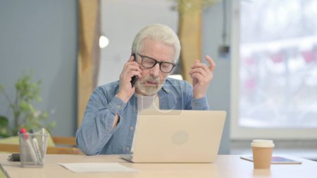 Foto de Senior Old Man using Phone and Laptop for Work - Imagen libre de derechos