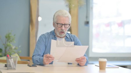 Photo for Senior Old Man Celebrating Win while Reading Documents in Office - Royalty Free Image