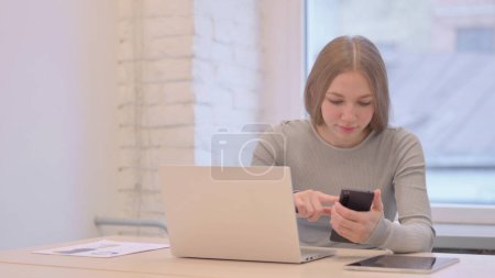 Téléchargez les photos : Creative Young Woman using Phone and Laptop for Work - en image libre de droit