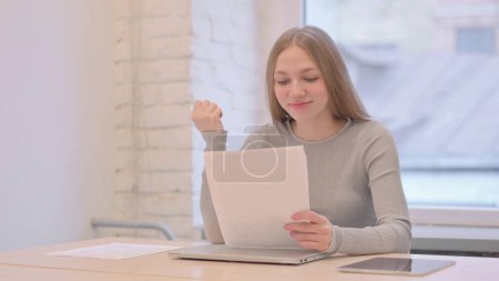 Téléchargez les photos : Creative Young Woman Celebrating while Reading Documents at Work - en image libre de droit