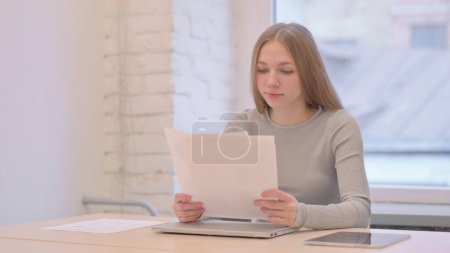 Photo for Creative Young Woman Upset while Reading Documents at Work - Royalty Free Image