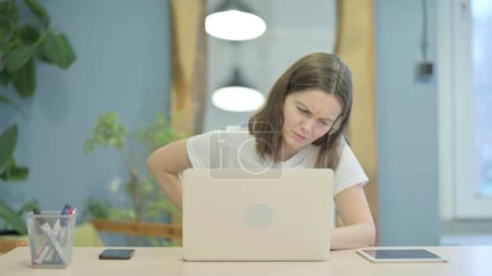 Téléchargez les photos : Young Woman having Back Pain while Sitting at Work - en image libre de droit