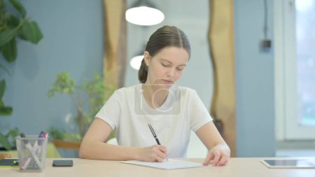 Téléchargez les photos : Young Woman Writing Letter at Work - en image libre de droit