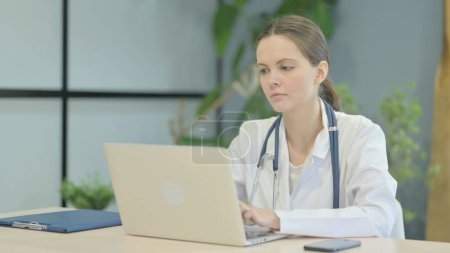 Téléchargez les photos : Jeune femme occupée médecin dactylographier sur ordinateur portable dans la clinique - en image libre de droit