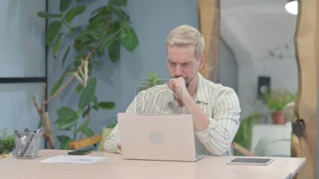 Téléchargez les photos : Modern Young Man Coughing while Working on Laptop - en image libre de droit
