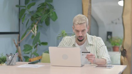Téléchargez les photos : Modern Young Man making Successful Online Payment on Laptop - en image libre de droit
