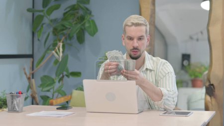 Téléchargez les photos : Modern Young Man Counting Dollar in Office - en image libre de droit