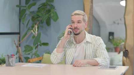 Téléchargez les photos : Modern Young Man Talking on Phone in Office - en image libre de droit