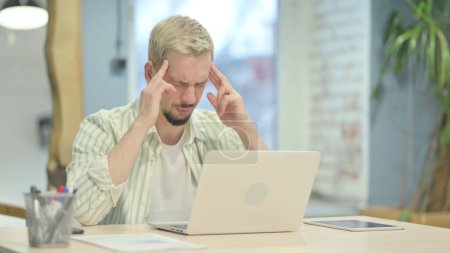 Téléchargez les photos : Stressé jeune homme avec maux de tête Travailler sur ordinateur portable - en image libre de droit