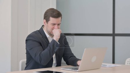 Foto de Empresario tosiendo mientras trabaja en el ordenador portátil - Imagen libre de derechos