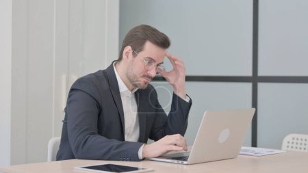 Foto de Empresario disgustado trabajando en el ordenador portátil en la ira - Imagen libre de derechos