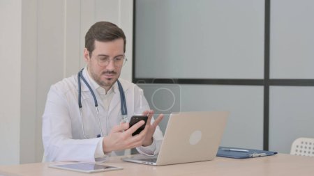 Photo for Doctor using Smartphone while using Laptop - Royalty Free Image