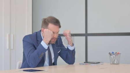 Téléchargez les photos : Homme d'affaires en colère dans la frustration assis dans le bureau - en image libre de droit
