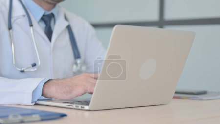 Téléchargez les photos : Gros plan du médecin travaillant sur ordinateur portable - en image libre de droit