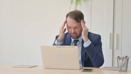Téléchargez les photos : Homme d'affaires souffrant de maux de tête Travailler sur un ordinateur portatif - en image libre de droit