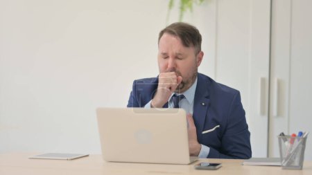 Téléchargez les photos : Homme d'affaires ayant la toux de travail sur ordinateur portable - en image libre de droit
