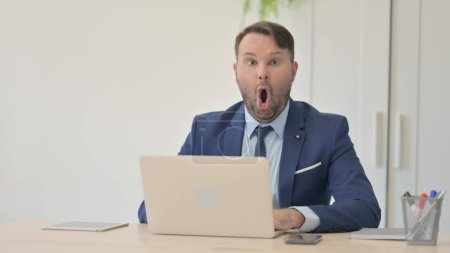 Téléchargez les photos : Choqué homme d'affaires travaillant sur ordinateur portable - en image libre de droit