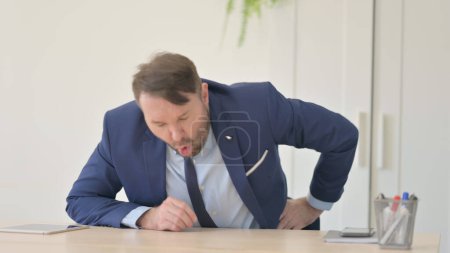 Téléchargez les photos : Homme d'affaires avec douleur au dos assis dans le bureau - en image libre de droit