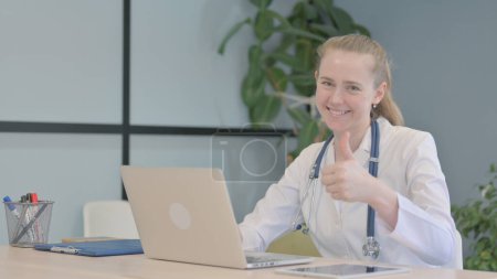 Téléchargez les photos : Pouces levées par le médecin féminin sur ordinateur portable dans la clinique - en image libre de droit