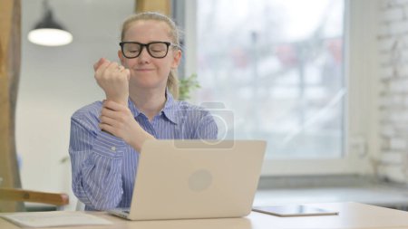 Téléchargez les photos : Jeune femme avec douleur au poignet travaillant sur ordinateur portable - en image libre de droit