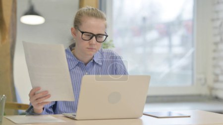 Téléchargez les photos : Jeune femme Document de lecture et de travail sur ordinateur portable - en image libre de droit