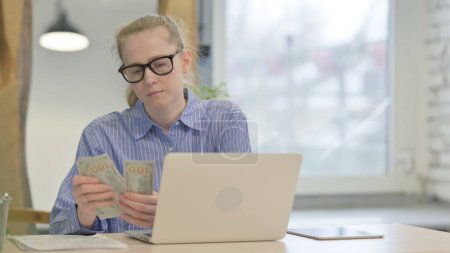 Téléchargez les photos : Jeune femme comptant des dollars au travail, faisant de l'argent - en image libre de droit