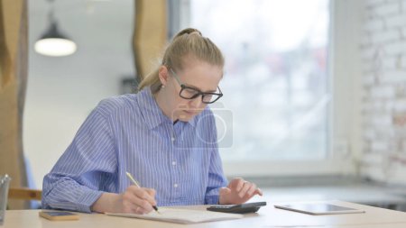 Téléchargez les photos : Jeune femme faisant des calculs à la paperasserie de travail - en image libre de droit